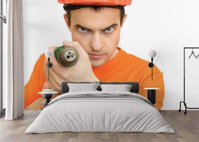 Handsome young guy with protective helmet on his, directs the camera hand electric drill, looking suspicious into the camera Wall mural