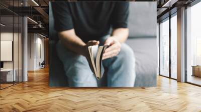 Christian man holds holy bible in hands. Reading the Holy Bible in a home. Concept for faith, spirituality and religion. Peace, hope Wall mural