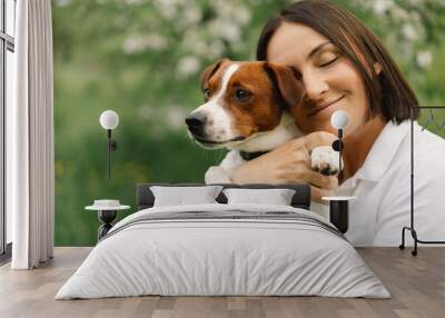 Woman play Jack Russell Terrier dog in meadow. Woman hugging Jack Russell Terrier dog in nature. Beautiful dog. Wall mural