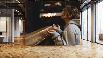 Woman praying on her knees in an ancient Catholic temple to God. Hands folded in prayer concept for faith, spirituality and religion. Peace, hope, dreams concept Wall mural