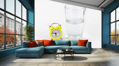 alarm clock, glass of water and pills on white background Wall mural