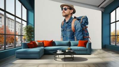 A man dressed in a denim shirt, sunglasses, a hat, and a backpack stands against a white background. Generative AI Wall mural