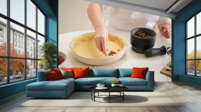 A woman pours pecan filling into a round pie. Process of cooking pecan pie in home kitchen for American Thanksgiving Day. Wall mural