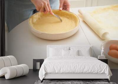 A woman prepares the dough for a pie by piercing it with a fork. Process of cooking pecan pie in home kitchen for American Thanksgiving Day. Wall mural