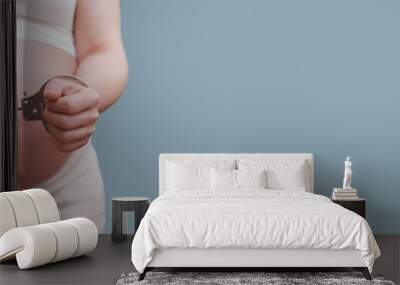 Chained hands of a pregnant woman, studio shot on a blue background, copy space with a place under the text on the prohibition of abortions Wall mural