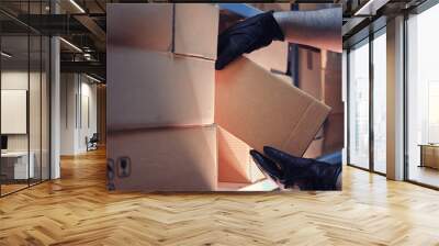 Hands of a man in leather gloves take a box of goods in a warehouse at night. Concept of security problems in warehouses and stores Wall mural