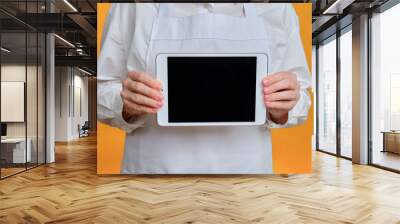 Man chef showing tablet screen on yellow studio background, mockup copy space Wall mural