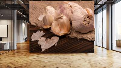 Heads of young garlic on a table covered with burlap, close-up, selective focus. Wall mural