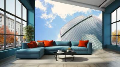 Low angle view of large skyscrapers covered with glass. Blue sky with some white clouds in the background. Modern office buildings theme. Wall mural