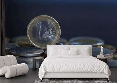 One euro coin of European Union stands above coins of other countries lying on wooden table. Theme of exchange rate changes. Wall mural