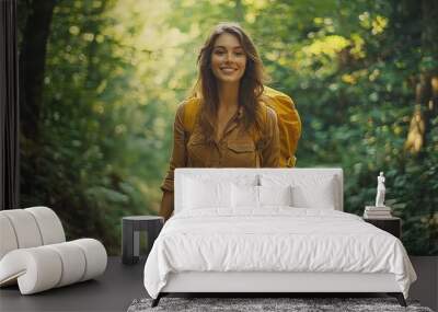 Young woman happily hiking in lush green forest wearing casual clothing and yellow backpack Wall mural