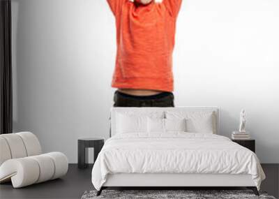 A joyful 9-year-old boy in an orange sweater and green trousers raised his hands up. The happiness of victory and celebration. Full height. Isolated on white background. Vertical. Wall mural