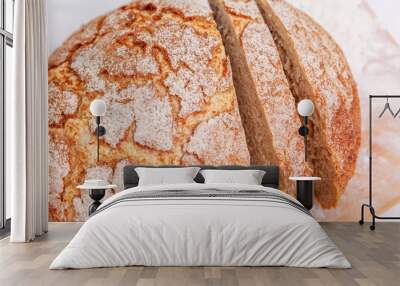 A sliced head of leavened self-made brown bread covered in flour on a table. Wall mural