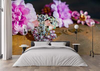 A composition of women's jewelry and accessories in pink on an old wooden surface. Brooch with colored stones, hairpins and flowers in delicate shades Wall mural