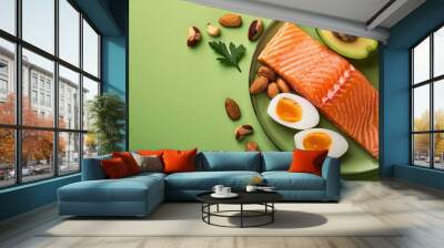 Ketogenic diet food selection including salmon, avocado, eggs, nuts and chia seeds on green background Wall mural