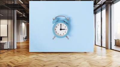 Retro alarm clock middle of blue background. Monochrome simple flat lay with pastel texture. Time concept. Stock photo. Wall mural