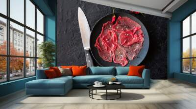 Marbled beef carpaccio with lemon, olive oil and Parmesan cheese on a black slate background. Top view, with copy space Wall mural