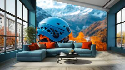 Autumn mountain view with helmet. A climbing helmet rests on a rocky outcrop, overlooking a vibrant autumn landscape with majestic mountains in the background. Wall mural