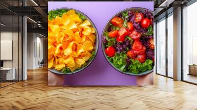 Two bowls of food, one with chips and the other with salad. The person holding the bowls is wearing red nail polish Wall mural