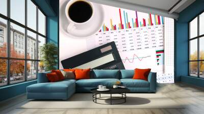 Black large calculator, a Cup of morning coffee and financial documents. Desktop of a businessman, company employee. Paperwork, budgeting. Chart with profit and sales growth. Wall mural