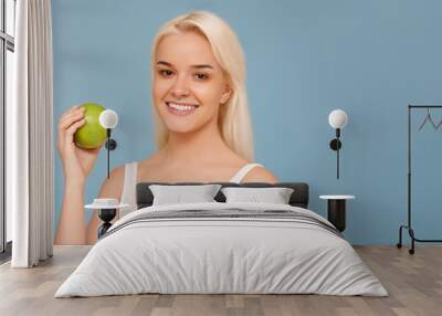 Woman with Apple. Beautiful girl with white smile on a blue background, healthy teeth. High Resolution Image Wall mural