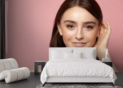 young girl combing her hair with clean skin, natural makeup and white teeth on a pink background Wall mural