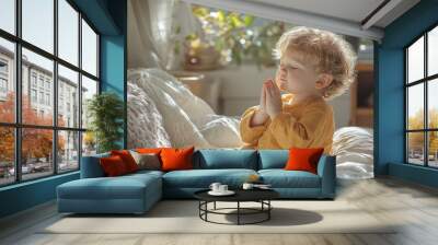 A boy in an orange T-shirt prays at home while reading the Holy Bible. Concept for faith, spirituality, and religion. Wall mural