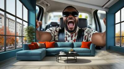 A joyful African American in glasses dances in a car and sings while driving. Wall mural