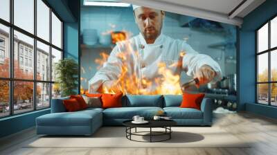 A professional chef prepares dishes in a pan with open flames. He works in a modern kitchen with different ingredients around. Wall mural