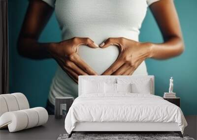 An attractive young woman with hands on her stomach forming a heart shape. Wall mural