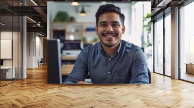 Angry Office Businessman Smiling at Camera. Latin IT Software Engineer Working at his Desk on a Laptop. Front View. Wall mural