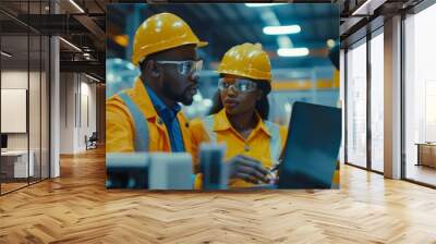 The background shows a team of diverse professionals wearing safety uniforms and hard hats working on a laptop computer. A black technician and a female worker talk during a meeting in a factory. Wall mural