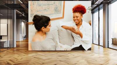 Two woman talk on the couch with coffee Wall mural