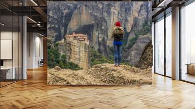 travel woman back to camera take photo by phone mobile device in hand from beautiful European rocky highland scenic landscape with monastery religion building on top of rock in Greece Wall mural