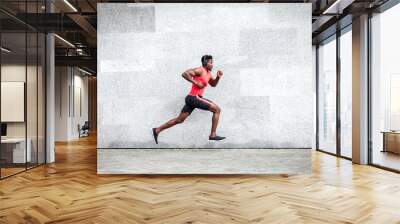 African American guy runner runs fast forward against the background of the city wall, sports man train on the street Wall mural