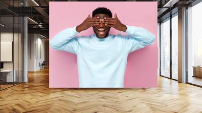 african american man in blue sweater closes his eyes and waits for surprise on pink isolated background Wall mural