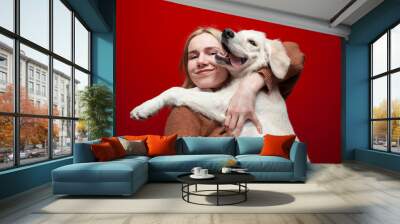 happy cheerful beautiful girl holding a dog on a red background, a woman hugs a golden retriever puppy and smiles, people with pets Wall mural