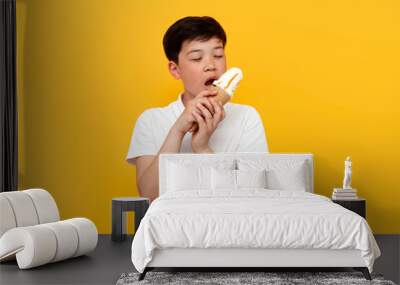 little asian boy holding ice cream and smiling on yellow background, korean kid with waffle cone eating sweet Wall mural