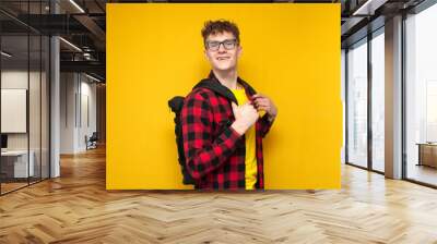 portrait of a student with a backpack on a yellow background, guy in glasses goes to college Wall mural