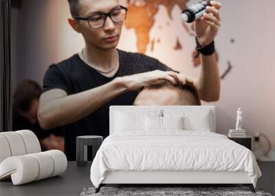 young barber kazakh works in a barbershop, handsome guy does hair styling for a client with dry gel in a hairdresser Wall mural