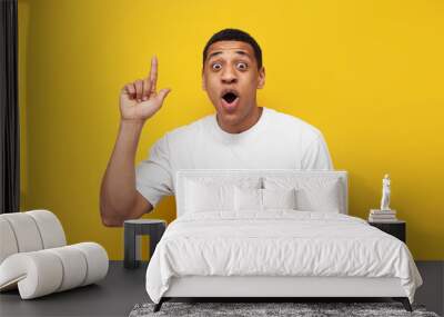 young surprised guy african american in white t-shirt shows thumb up on yellow isolated background Wall mural