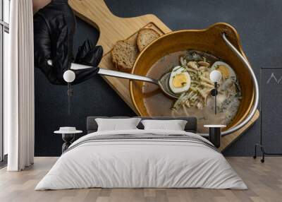 A bowl of soup with two pieces of bread on a wooden board. Wall mural