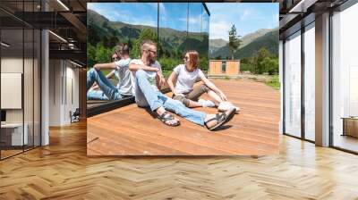 Beautiful man and woman are sitting on the terrace at home in nature. The concept of relaxing pastime, friendship and relaxation together Wall mural