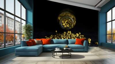 Gold stones in the darkness, on a dark background, slept from the bottle, yellow stones, gold, in close-up, still life Wall mural