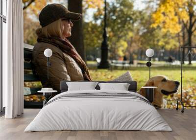 Woman reading book on park bench in autumn with dog by her side Wall mural