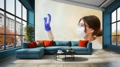 Pretty young female doctor with protective workwear holding test tube. Female doctor with face mask gloves in Hospital. Science, chemistry, biology, medicine. Lab concept
 Wall mural