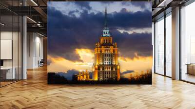 Awe view on illuminated tower with spire of Hotel Ukraina against evening cloudy sky in Moscow, Russia. Soviet stalinist architecture Wall mural