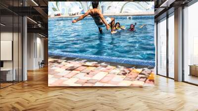 Happiness family,  preteen daughters and father playing , splashing each other with water in the pool. Man jumping to the blue pool Wall mural