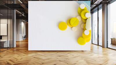 white and yellow pills and medical mask on white wooden background. Copy space. Wall mural