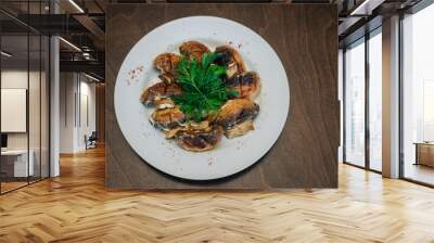 Baked mushrooms with herbs on a white round plate. Wall mural